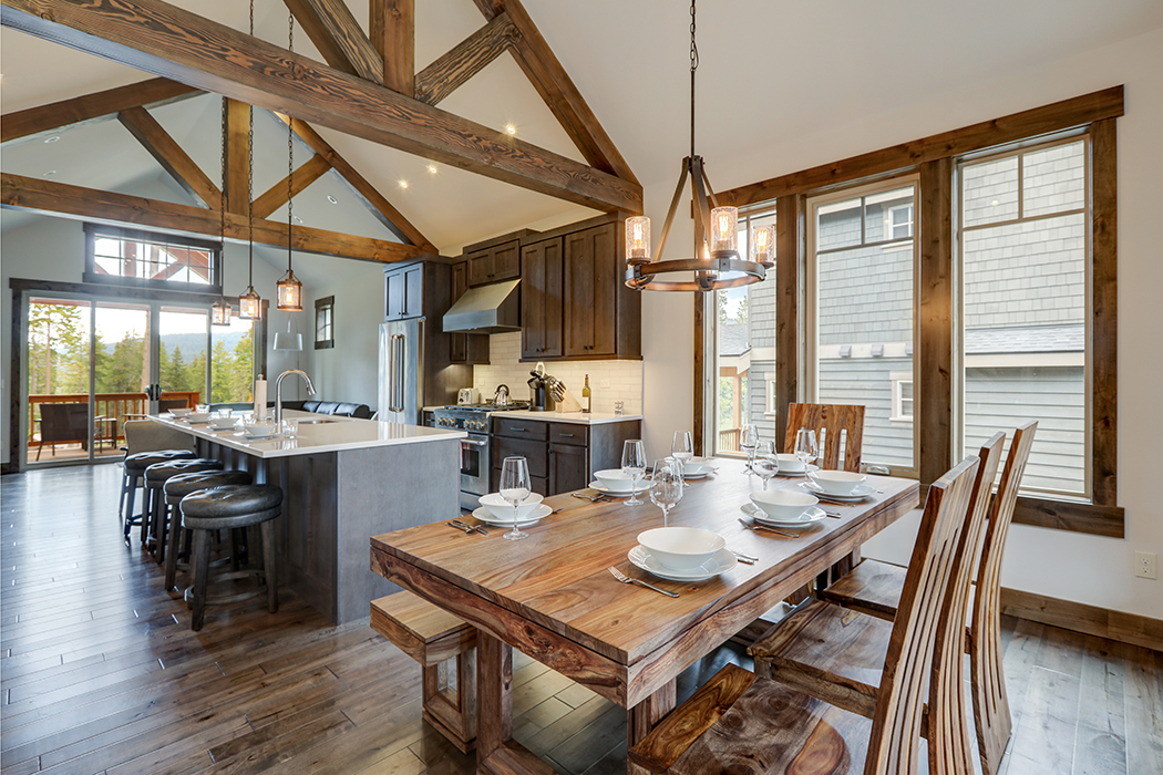 Amazing dining room near modern and rustic luxury kitchen with vaulted ceiling and wooden beams, long island with white quarts countertop and dark wood cabinets.